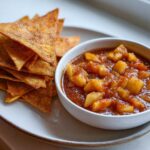 A bowl of chunky Apple Pie Salsa served next to a stack of crispy Cinnamon Sugar Chips.