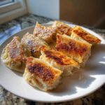 A plate of perfectly pan-fried dumplings with crispy, golden-brown bottoms, showcasing the delicious texture of these easy dumplings.