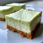 A close-up of a thick slice of Key Lime Cheesecake Bars showing the graham cracker crust and creamy filling.