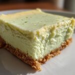 A close-up, featured image of a single, thick square of Key Lime Cheesecake Bars with a graham cracker crust.