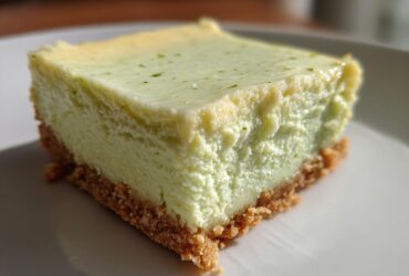 A close-up, featured image of a single, thick square of Key Lime Cheesecake Bars with a graham cracker crust.