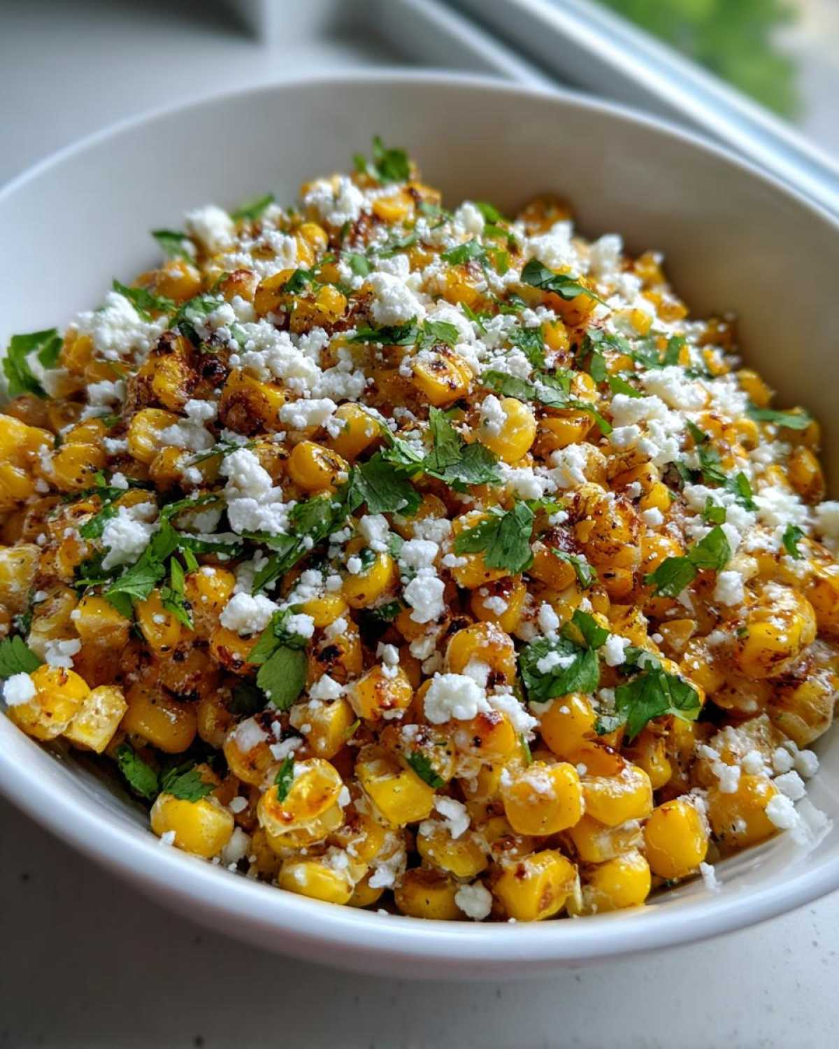 A close-up view of Mexican Street Corn Salad featuring charred corn kernels topped with crumbled white cheese and fresh cilantro.