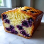 Close-up of a moist, golden Blueberry Loaf Bread studded with dark purple blueberries.