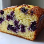Close-up of a moist slice of Blueberry Loaf Bread showing the tender crumb and dark purple blueberries.