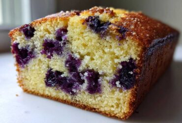 Close-up of a moist slice of Blueberry Loaf Bread showing the tender crumb and dark purple blueberries.