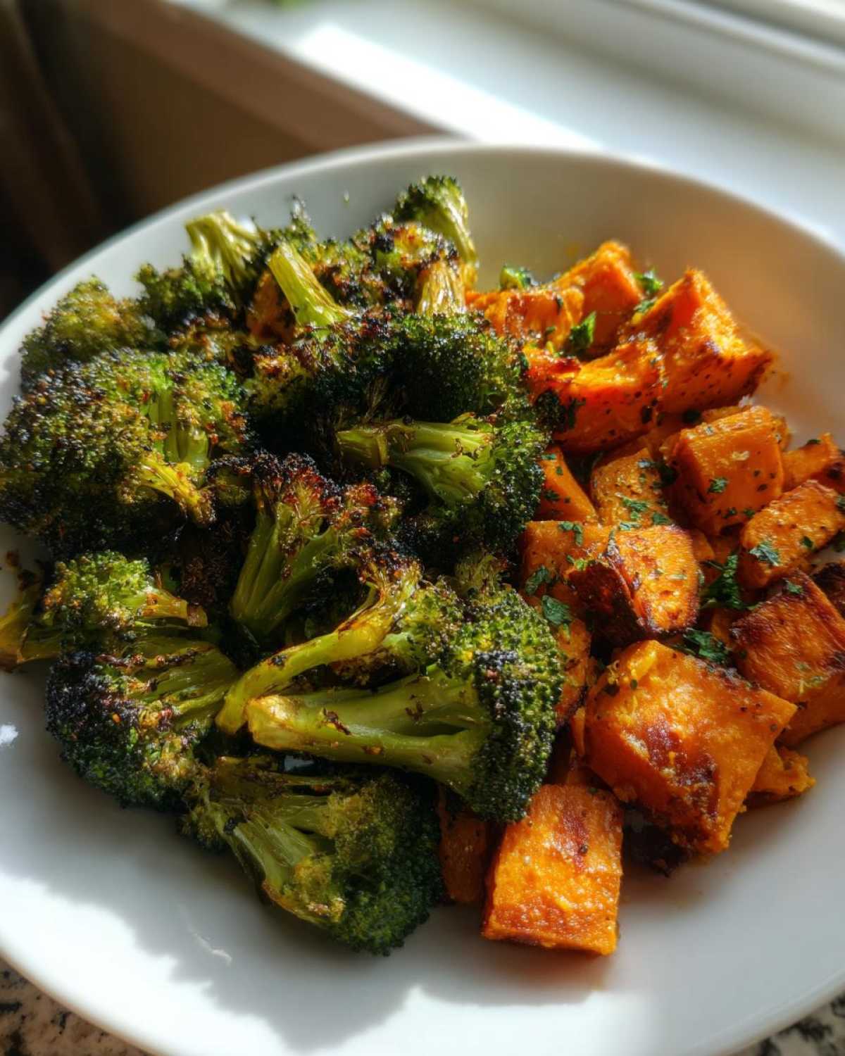 A close-up of perfectly Roasted Broccoli and Sweet Potatoes served together in a white bowl.