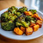 Close-up of perfectly Roasted Broccoli and Sweet Potatoes, slightly charred and seasoned, served on a white plate.