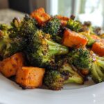 Close-up of perfectly Roasted Broccoli and Sweet Potatoes, slightly charred and seasoned, served on a white plate.
