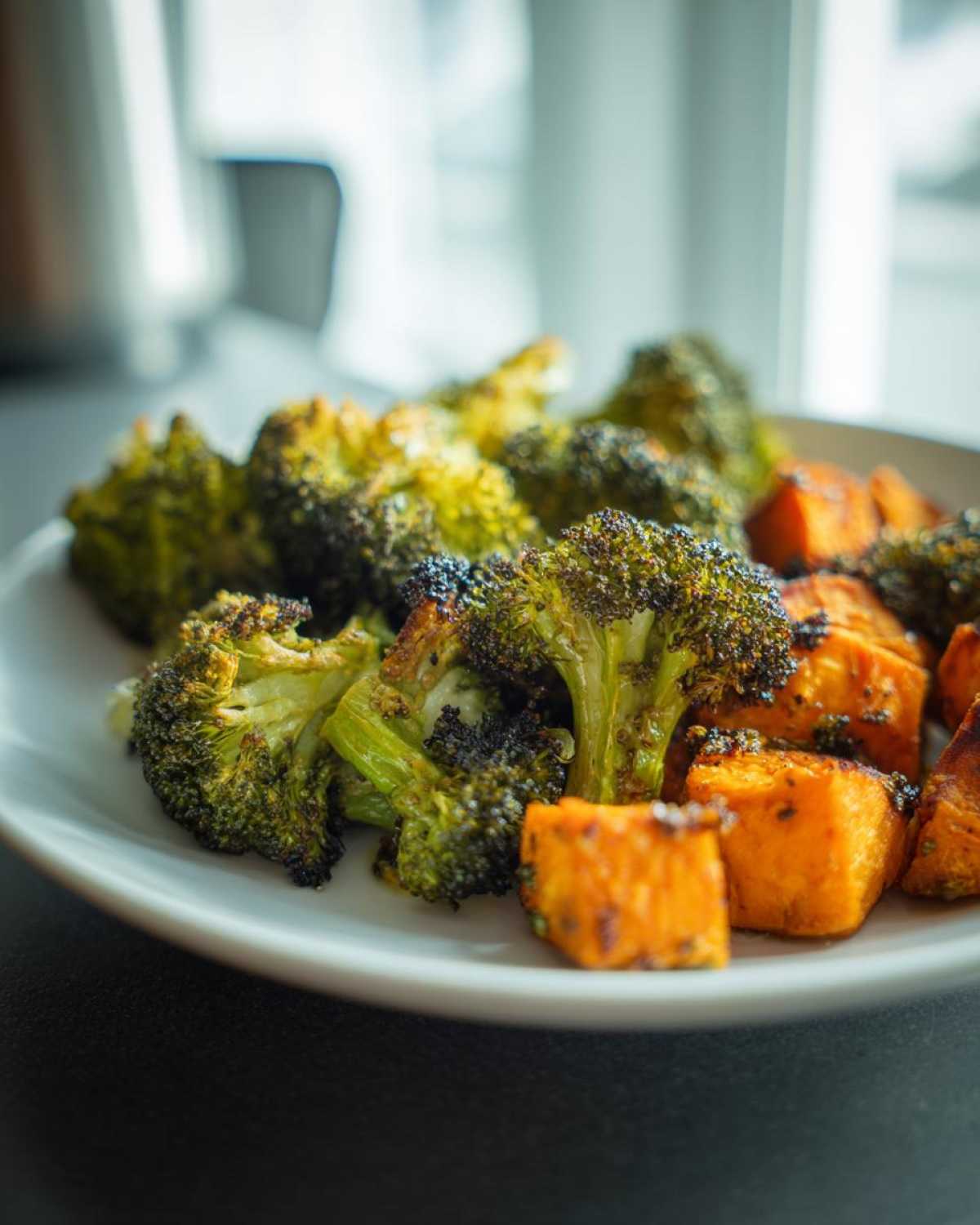 Close-up of perfectly seasoned Roasted Broccoli and Sweet Potatoes served on a white plate.