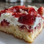 Close-up of a moist slice of Strawberry Shortcake Bars featuring a thick cake base, whipped cream, and glazed strawberries.