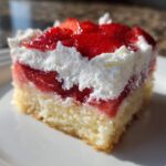 A close-up of a layered Strawberry Shortcake Bars slice featuring cake, strawberry filling, and whipped cream.