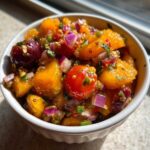 Close-up of vibrant Peach Cherry Salsa featuring diced peaches, whole cherries, and red onion in a white ramekin.